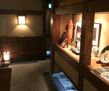 Atmospheric wooden entry corridor with lit display alcoves at Yadoya Kikokuso in Kyoto, Kansai