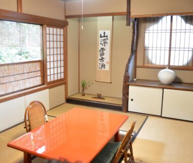 Japanese tatami room with low lacquered table, shoji screens, tokonoma alcove and round window at Yadoya Manjiro Kyoto