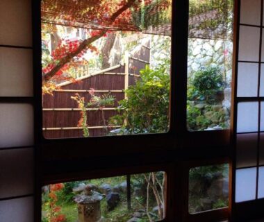 Tatami room with shoji screens framing a small garden with autumn foliage at Yadoya Manjiro, Kyoto
