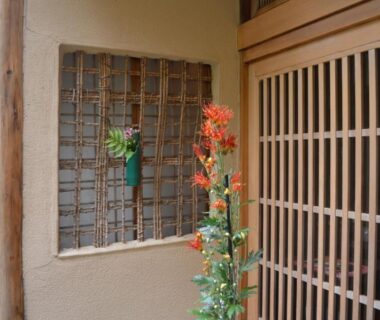 Wooden lattice sliding door with decorative floral arrangement at Yadoya Manjiro Kyoto
