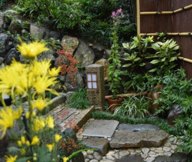 Stone stepping path with lantern and yellow flowers at Yadoya Manjiro ryokan garden in Kyoto