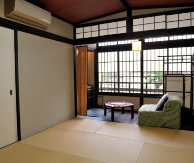Tatami room with low table, green floor chair and shoji lattice windows at Yadoya Nishijinso Kyoto