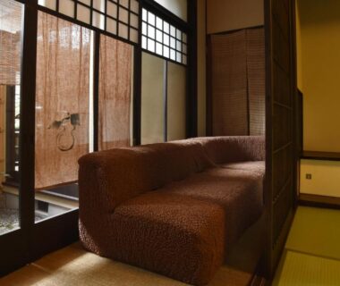 Tatami room corner with low upholstered sofa, shoji screens and sliding doors opening to a small courtyard