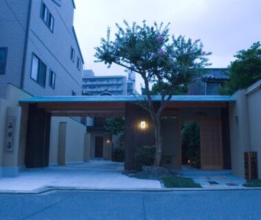 Lantern-lit entrance gate and tree at Yadoya Nishijinso, Kyoto