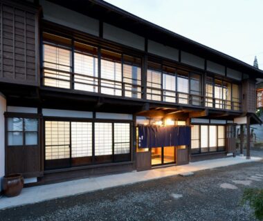 Two-story wooden ryokan with shoji screens and blue noren entrance in Nagano, Chūbu region