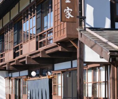 Wooden facade with shoji windows and noren at entrance of Yadoya Shiroganeya in Nagano