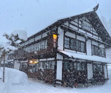 Traditional wooden ryokan exterior in heavy snowfall at Yadoya Shiroganeya, Nagano
