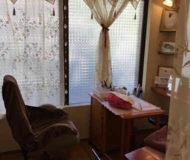 Swivel chair and small table by lace-curtained frosted window at Yakushi no Yu Yumotokan, Gunma