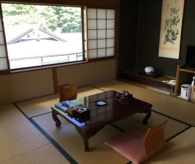 Traditional tatami room with low table, floor chairs and shoji screens at Yakushi no Yu Yumotokan, Gunma