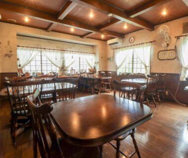Wood-paneled ryokan dining room with wooden tables and curtained windows at Yama no Ie in Tochigi