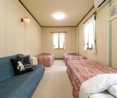 Bright twin bedroom with two beds, blue sofa and windows at Yama no Ie in Tochigi