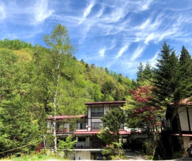 Traditional ryokan building nestled in a forested hillside at Yama no Yado Meiji Onsen, Nagano