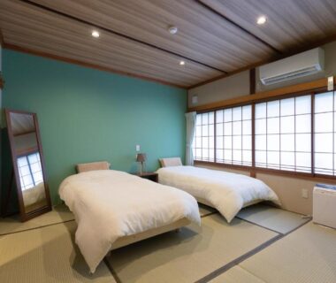 Tatami-floored room with two raised beds, shoji screens and green accent wall at Yamabiko, Nagano