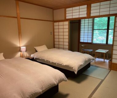 Tatami room with twin beds, shoji screens and greenery outside at Yamabiko, Nagano, Chūbu, Japan
