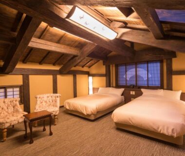 Japanese-style room with two beds, exposed wooden beams and shoji screens at Yamabiko Ryokan, Kumamoto
