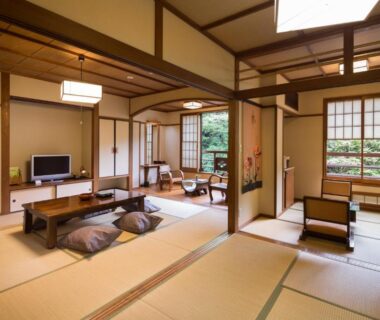 Spacious tatami room with low table and shoji screens overlooking garden at Yamabiko Ryokan, Kumamoto