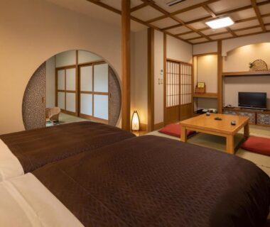 Tatami-style room with twin beds, low table and shoji screens at Yamabiko Ryokan, Kumamoto