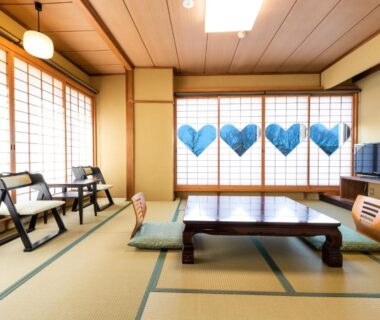 Tatami room with low wooden table, zabuton cushions, zaisu chairs and shoji screens at Yamadaya Ryokan, Kyoto