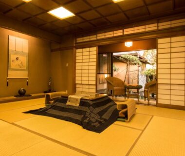 Traditional tatami room with blanketed low table, tokonoma alcove, shoji screens opening to small garden at Yamagaso, Kanagawa