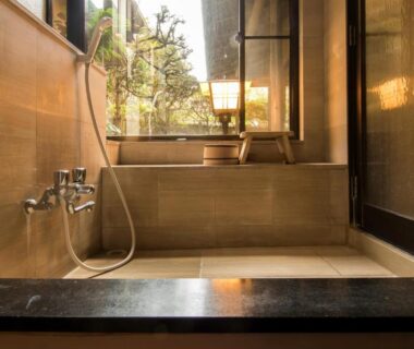 Interior soaking tub with handheld shower and window view of greenery at Yamagaso, Kanagawa