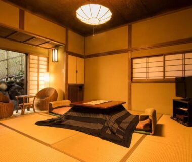 Tatami room with low table, shoji screens and wicker chairs opening to a small garden at Yamagaso Kanagawa