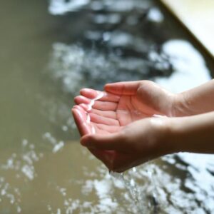 Cupped hands touching warm onsen water at Yamagataya ryokan in Fukushima Tohoku