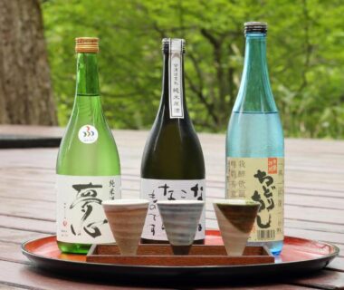 Three sake bottles and cups on a lacquer tray on a wooden deck at Yamagataya, Fukushima, Tōhoku