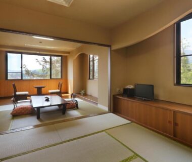 Traditional tatami room with low table, floor chairs, large windows and wooden cabinet at Yamagataya in Fukushima