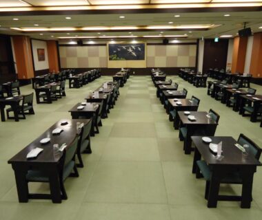 Large tatami dining hall with rows of low lacquered tables set for group meals at Yamagisi Ryokan, Yamanashi