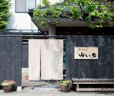 Traditional noren entrance with wooden facade, potted plants and bench at Yamaichi in Iwate, Tōhoku