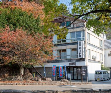 Exterior of Yamaichi Bekkan with autumn trees and colorful banners along the street in Hiroshima