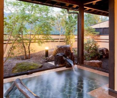 Covered stone onsen with wooden beams, handrail and small garden at Yamakikan, Gunma, Kantō