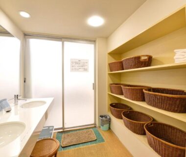 Washbasins and wicker basket shelves beside frosted door in Yamamoto Ryokan changing area, Kyoto