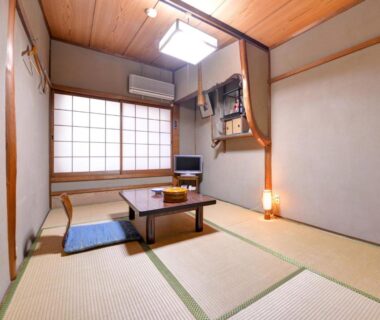 Traditional tatami room with low table, zabuton cushions and shoji screens at Yamamoto Ryokan, Kyoto
