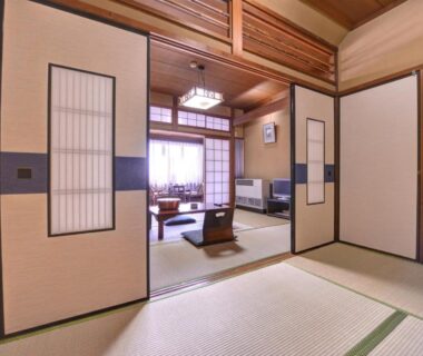 Traditional tatami room with low dining table, shoji screens, and seating area at Yamamoto Ryokan in Kyoto