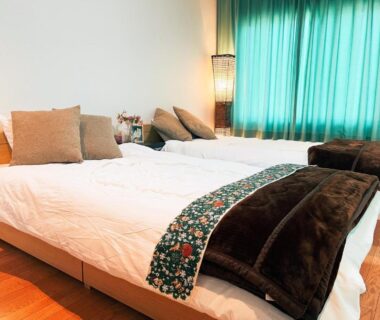 Bright twin bedroom with wooden floor, green curtains and decorative runners at Yamanaka Lake Ryozan in Yamanashi