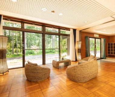 Sunlit lounge with wicker seating and large glass doors at Yamanaka Lake Ryozan, Yamanashi, Chūbu