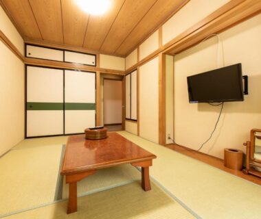 Tatami room with low lacquer table, fusuma sliding doors and wall-mounted TV at Yamanaka Lake Ryozan, Yamanashi