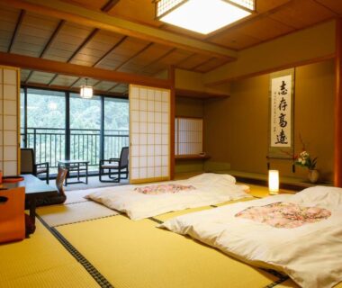 Tatami room with shoji screens, futon bedding and balcony at Yamanaka Onsen Hanatsubaki, Ishikawa
