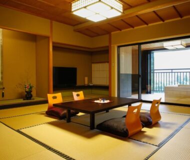 Traditional tatami room with low table, floor chairs and tokonoma alcove opening to balcony at Yamanaka Onsen Ishikawa