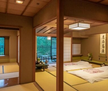 Tatami room with futons, shoji screens and balcony overlooking greenery at Yamanaka Onsen Hanatsubaki Ishikawa