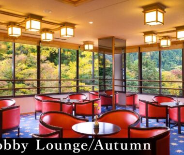 Lobby lounge with red round chairs, low tables and large windows overlooking autumn foliage at Yamanaka Onsen Kagari Kisshotei Ishikawa