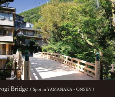 Kohrogi Bridge leading to ryokan buildings flanked by green trees in Yamanaka Onsen, Ishikawa, Chūbu