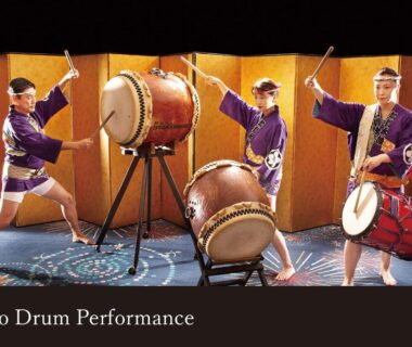 Three taiko drummers in purple robes performing with large drums before gold folding screens at Yamanaka Onsen Kagari Kisshotei, Ishikawa