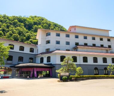 Front exterior of Yamanaka Onsen Kajikaso with entrance canopy and hillside backdrop in Ishikawa, Chūbu