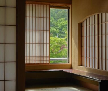 Tatami room with shoji screens and wooden bench overlooking green hillside at Yamanakaonsen Hanamurasaki