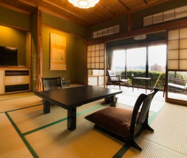 Traditional tatami room with low table, zabuton floor chairs, shoji screens and balcony overlooking greenery