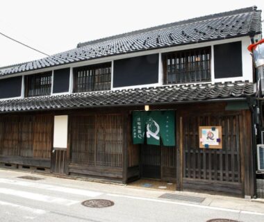 Two-story wooden facade with green noren at Yamasaki Ryokan Q Nakamonzenya in Hyōgo