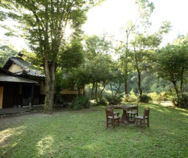 Wooden table and chairs on grassy garden beside traditional ryokan, Yamashinobu, Kumamoto, Kyūshū, Japan