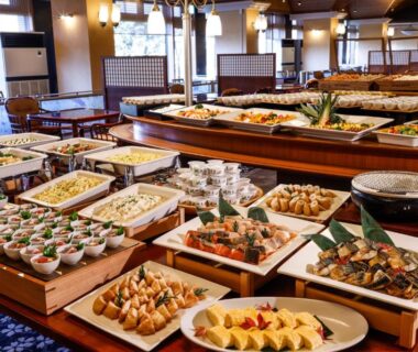 Buffet spread of assorted Japanese dishes on wooden counters in a ryokan dining hall, Ishikawa